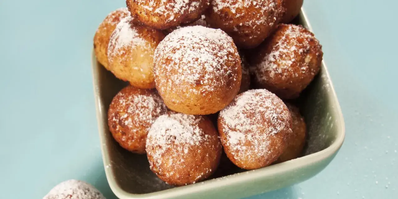Ein Schüsselchen voller goldbrauner Mutzen, bestäubt mit Puderzucker. Ein köstliches original Mutzen Rezept zum Nachbacken.