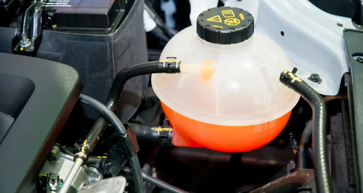 A car's coolant reservoir, showing the orange fluid level. This helps determine how much coolant does a car take.