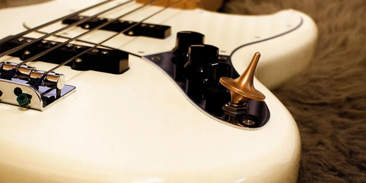 Ein weißes Bassmusikinstrument mit vier Saiten und einem bronzenen Kreisel auf dem Bedienfeld.