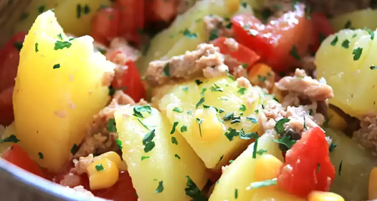 Salade de pommes de terre, thon, tomates et maïs, parsemée de persil frais. Un plat simple et savoureux.