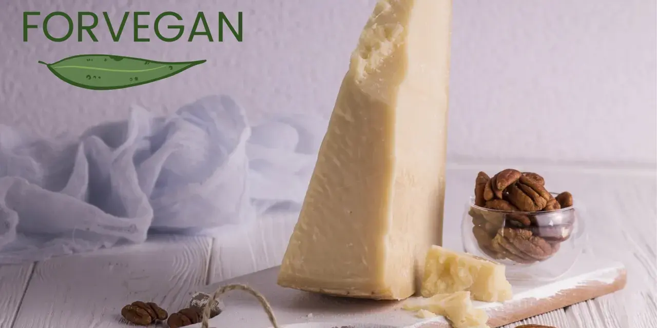 Kawałek sera parmezan, orzechy pekan w szklanej miseczce i liść z napisem FORVEGAN.