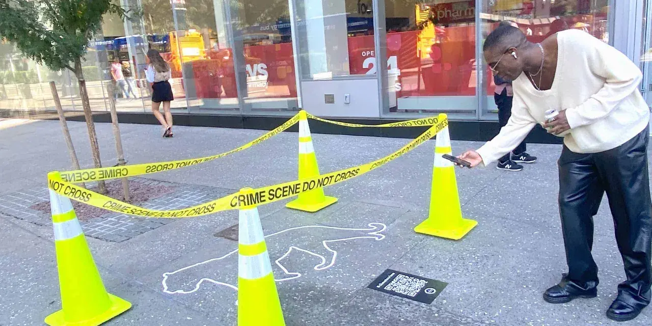 Ein Mann scannt mit seinem Handy einen QR-Code neben einer Kreideumriss-Leiche. Ein cleveres Guerilla-Marketing-Event.