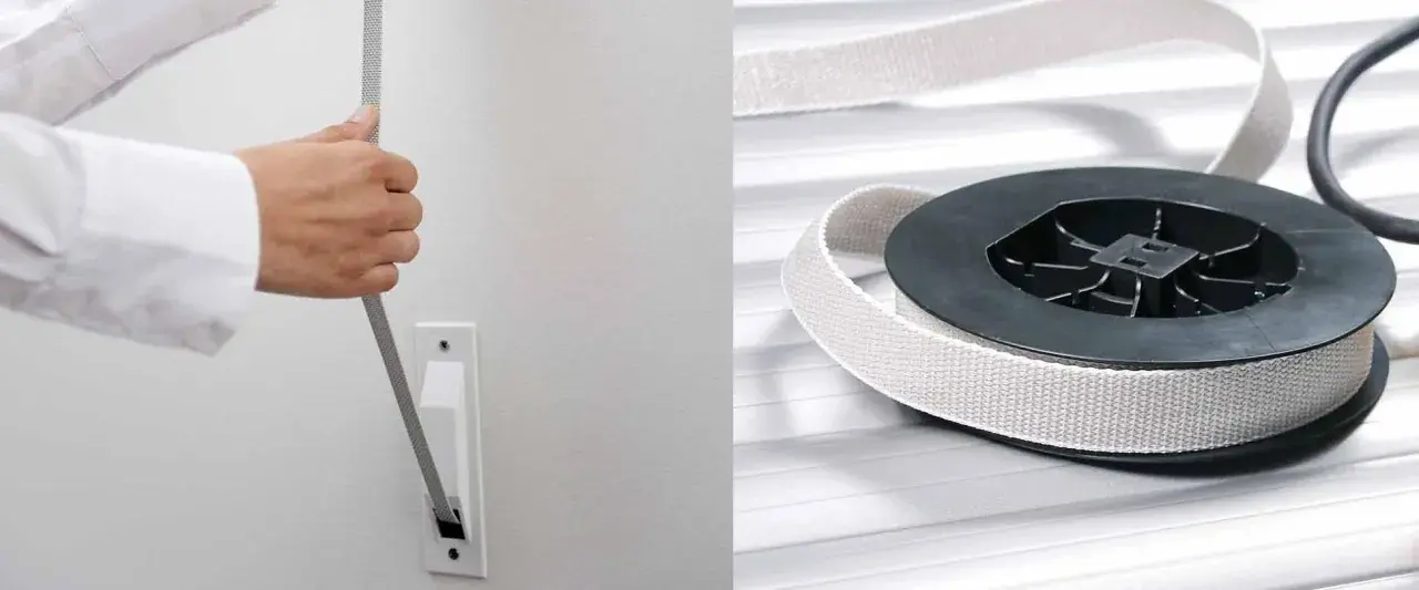Ein gerissenes Rolladenband wird aus einer Wandhalterung gezogen. Daneben liegt ein neues Band auf einer Rolle.