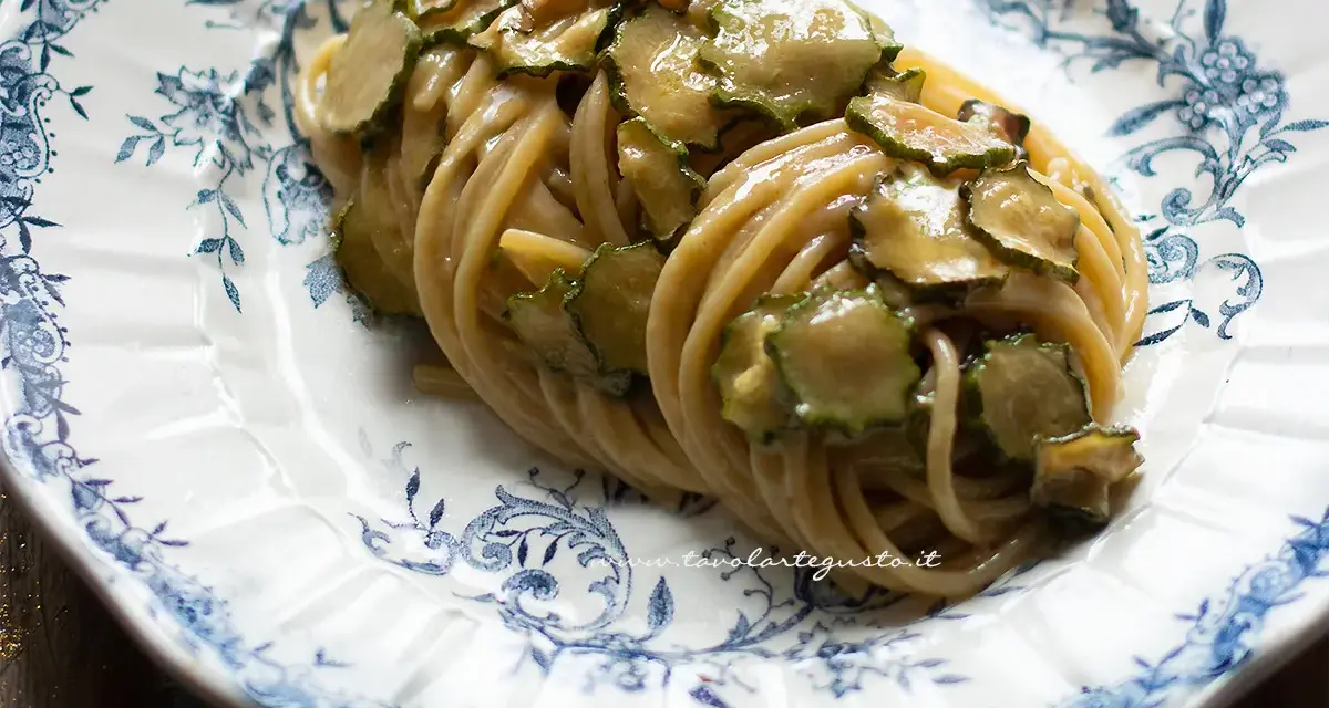Un piatto di spaghetti alla nerano ricetta, conditi con zucchine saltate e una cremosa salsa al formaggio, serviti su un piatto decorato.