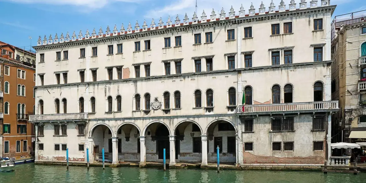 Palazzo sul Canal Grande, un tempo sede dei mercanti tedeschi, con le sue arcate e finestre che riflettono l'acqua di Venezia.