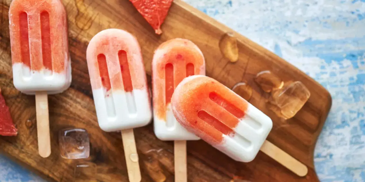 Erfrischendes Erdbeereis auf Holzbrett, mit Eiswürfeln und Grapefruitstücken. Perfekt für heiße Tage, wenn man Kalorien im Blick behält.
