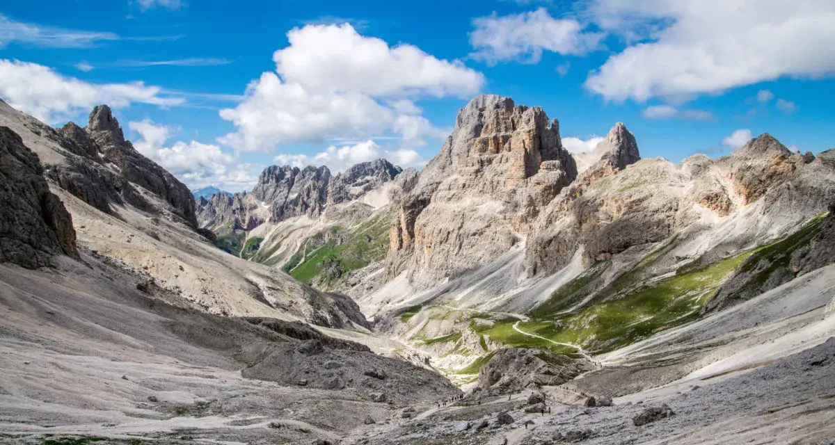 Malownicze **Val di Fassa** w Dolomitach. Kręta ścieżka prowadzi przez skaliste zbocza i zielone hale ku majestatycznym szczytom.