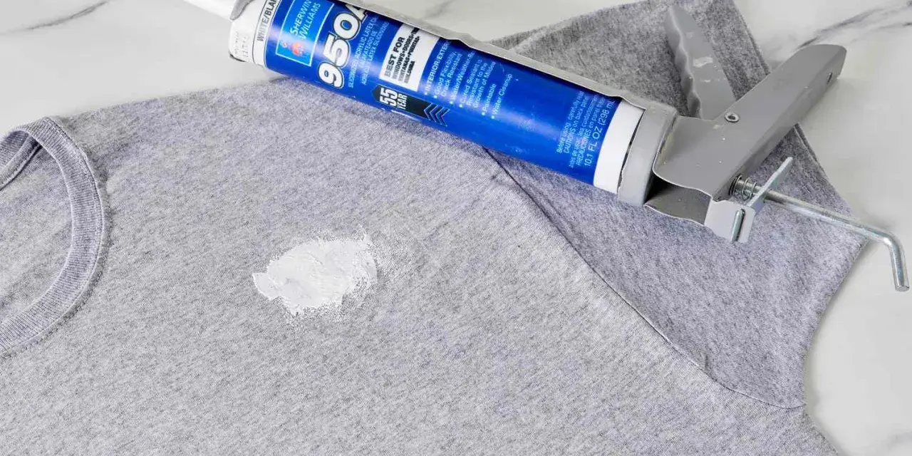 Zaschnięty silikon na szarym T-shircie i pistolet do jego aplikacji. Dowiedz się, jak usunąć zaschnięty silikon z ubrania.