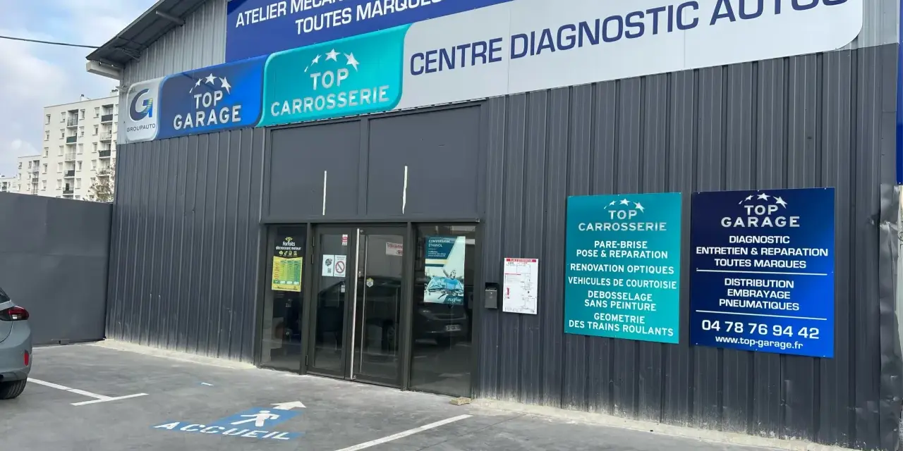 Façade d'un centre automobile avec des panneaux "Top Garage", "Top Carrosserie" et "Centre Diagnostic Autos".