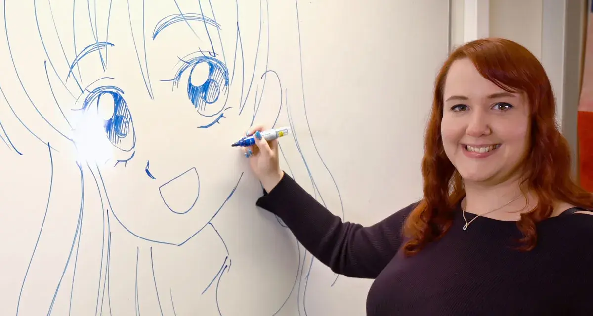 En kvinna med rött hår ritar en stor manga teckning på en whiteboard.