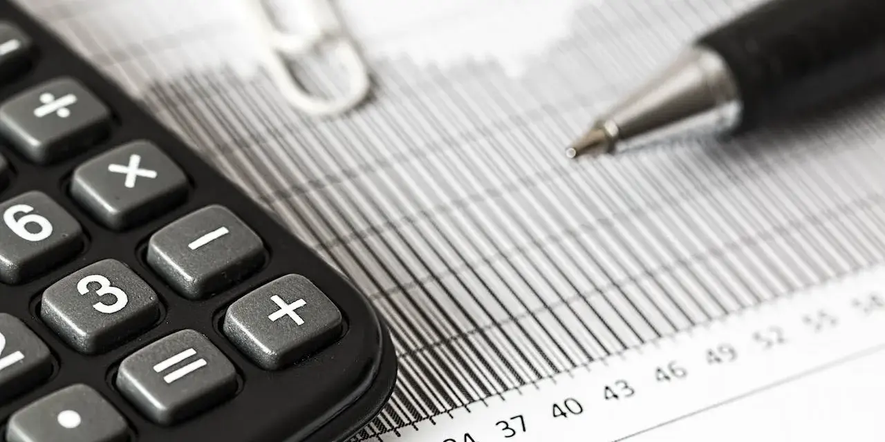 Calculadora y bolígrafo sobre gráficos. El modelo 309 para que sirve se puede deducir de estos elementos de contabilidad.
