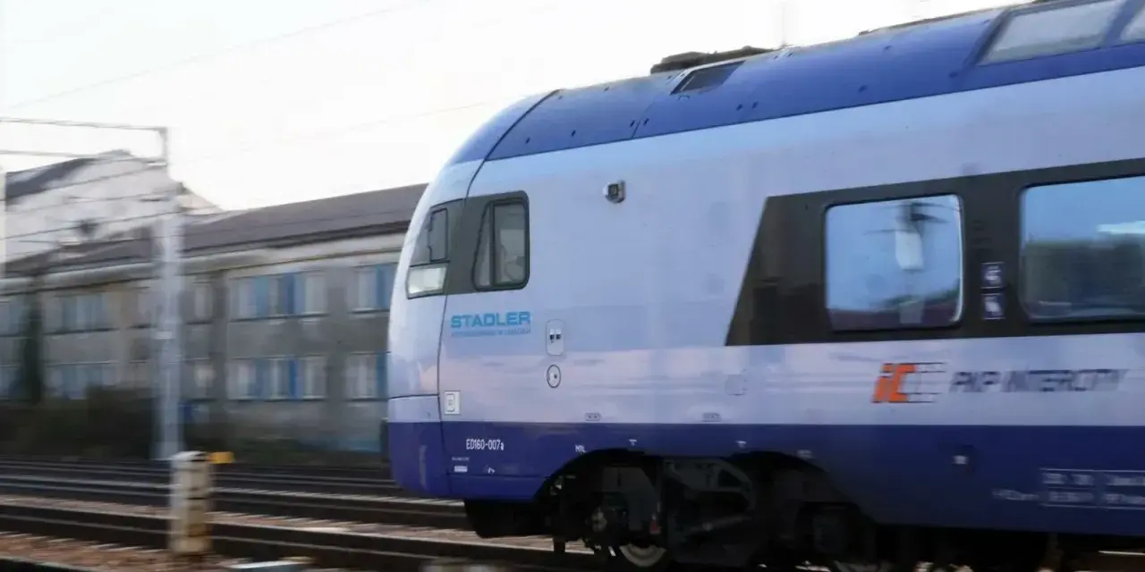 Pociąg PKP Intercity Stadler ED160-007 mija budynek. Może to być widok podczas przebukowania biletu na podróż.