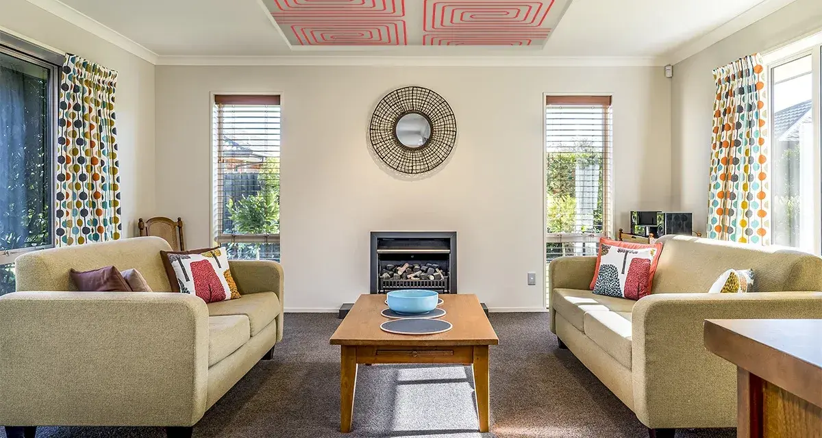 Sala de estar con sofás, chimenea y un moderno techo radiante con patrón de espiral roja.