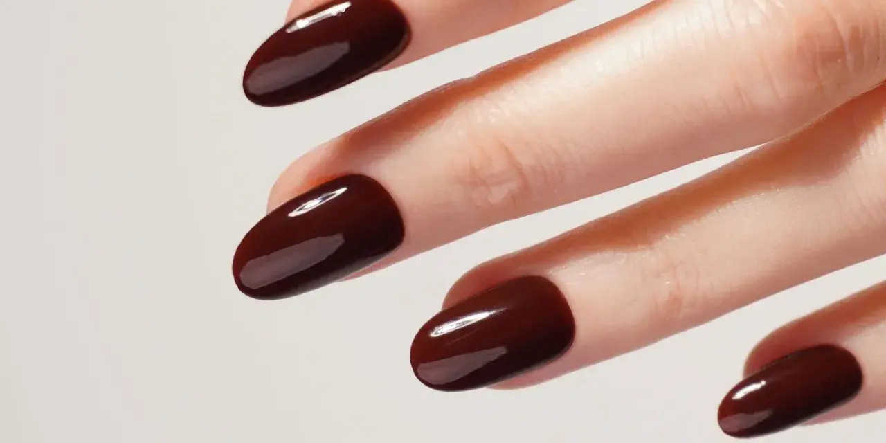 Une idée manucure automne : des ongles courts et arrondis, vernis d'un brun chocolat profond et brillant, évoquant la douceur des feuilles mortes.