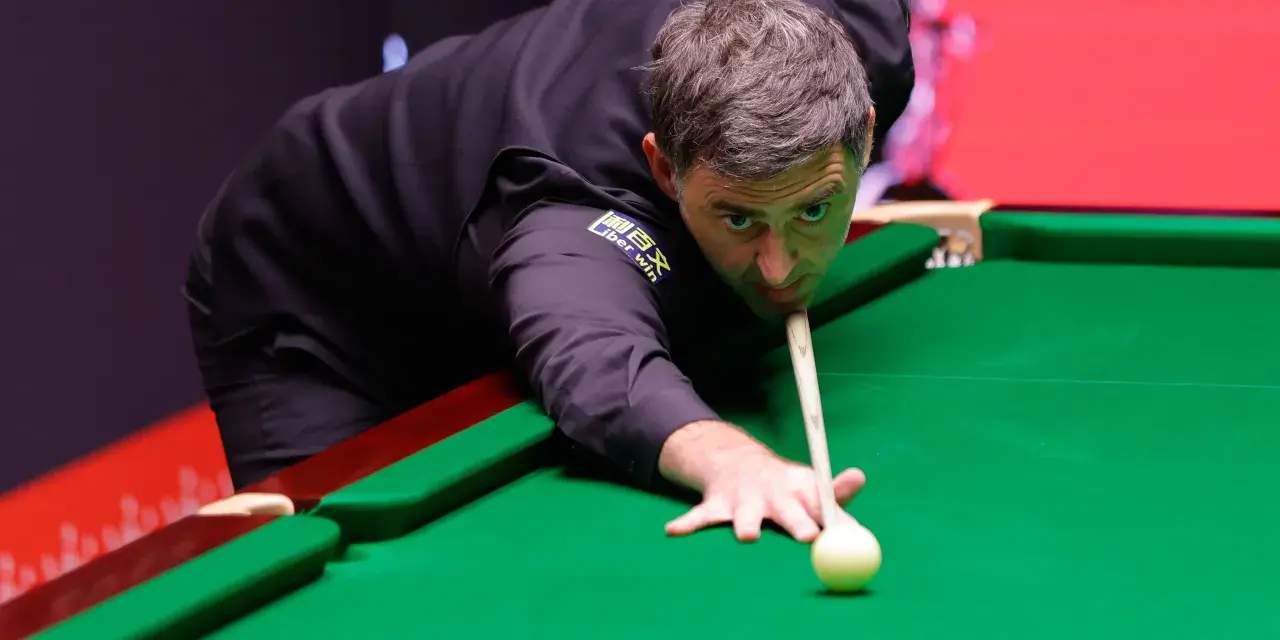 Ronnie O'Sullivan, jeden z najlepsi snookerzyści wszechczasów, skupiony przy zielonym suknie, celuje w bilę.