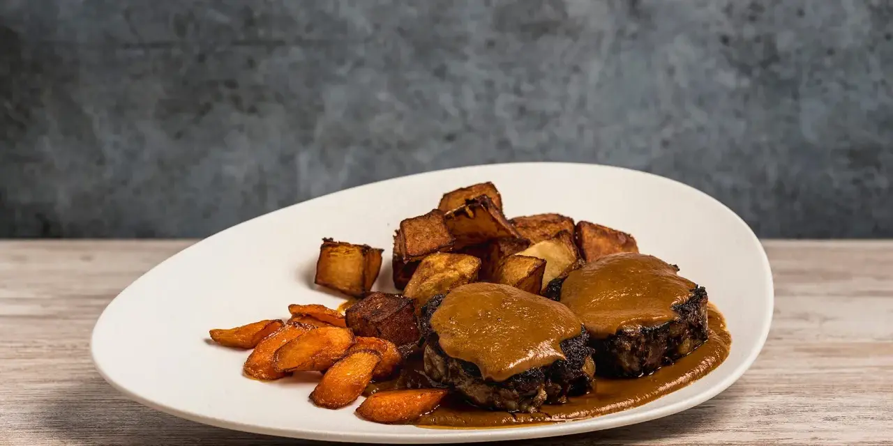 Delicioso rabo de toro bañado en salsa, acompañado de patatas rústicas y zanahorias glaseadas.