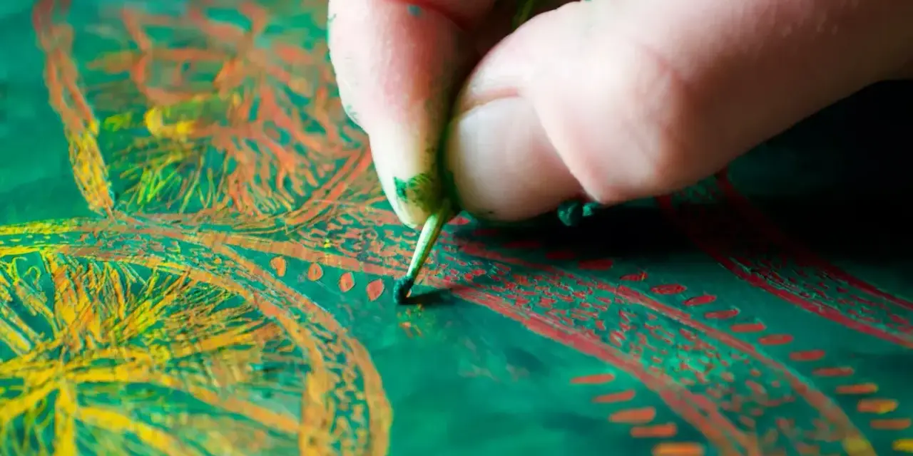 Main d'un artiste peintre travaillant sur une peinture à l'huile aux couleurs vives.