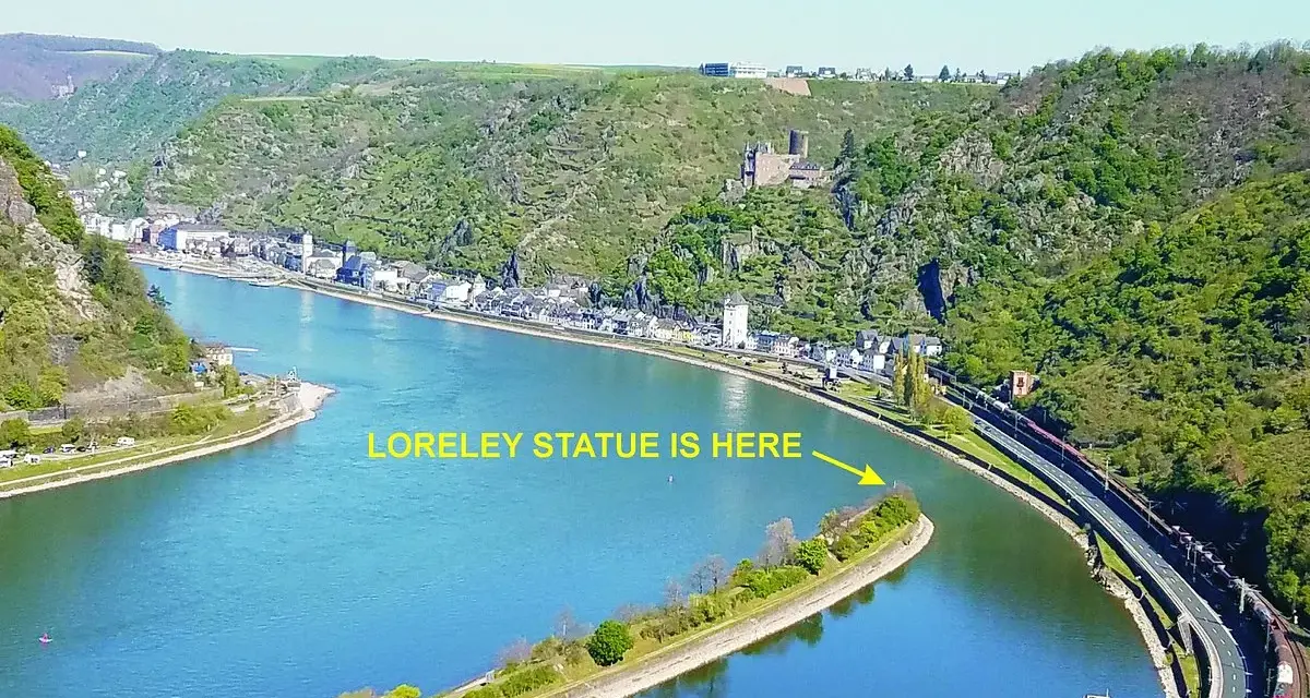 En vidsträckt vy över Loreleis flod, med en stad längs stranden och en järnväg som löper längs floden.