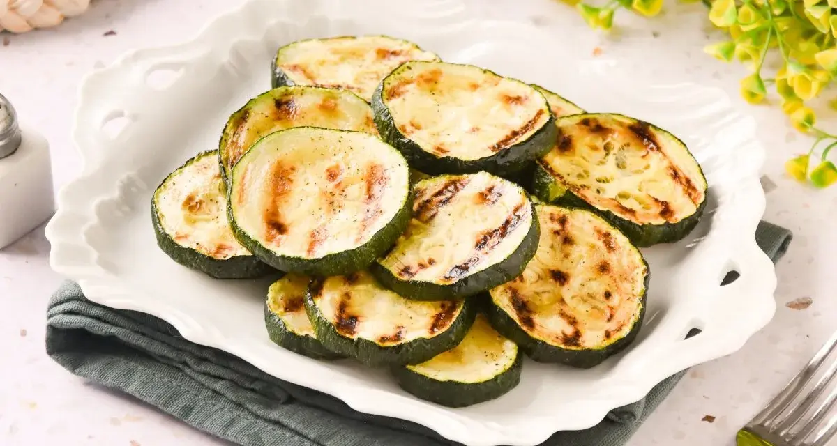 Rodajas de calabacín a la plancha, tiernas y con marcas de parrilla, servidas en un plato blanco.