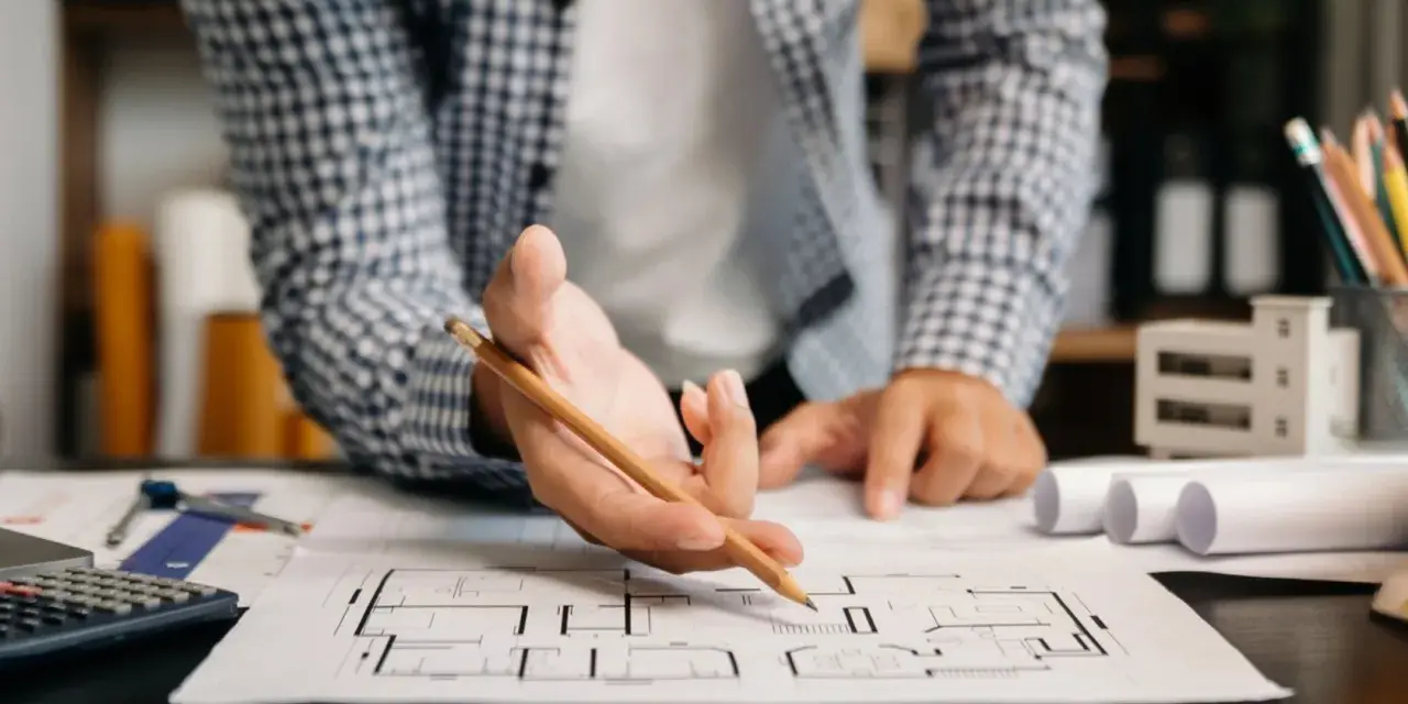 Architekt analizuje plany mieszkania, zastanawiając się, dlaczego od 2026 roku każde mieszkanie na sprzedaż musi mieć audyt akustyczny.