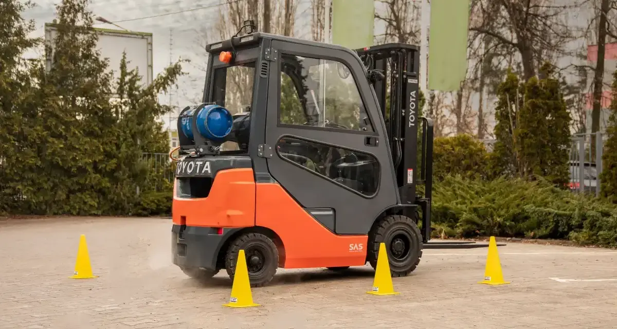 Pomarańczowy wózek widłowy Toyota na placu manewrowym. Idealne miejsce na kurs na wózek widłowy Kraków.