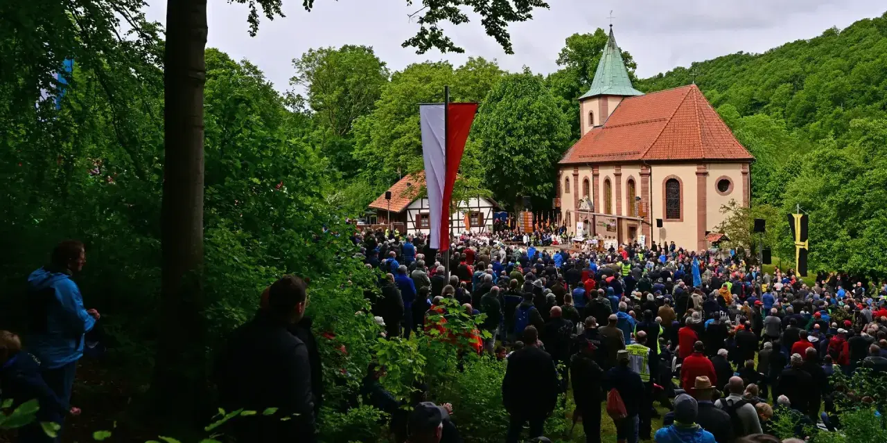 Große Menschenmenge versammelt sich vor einer Kirche zu Christi Himmelfahrt. Fahnen wehen, ein Gottesdienst findet statt, inspiriert von der Bibel.