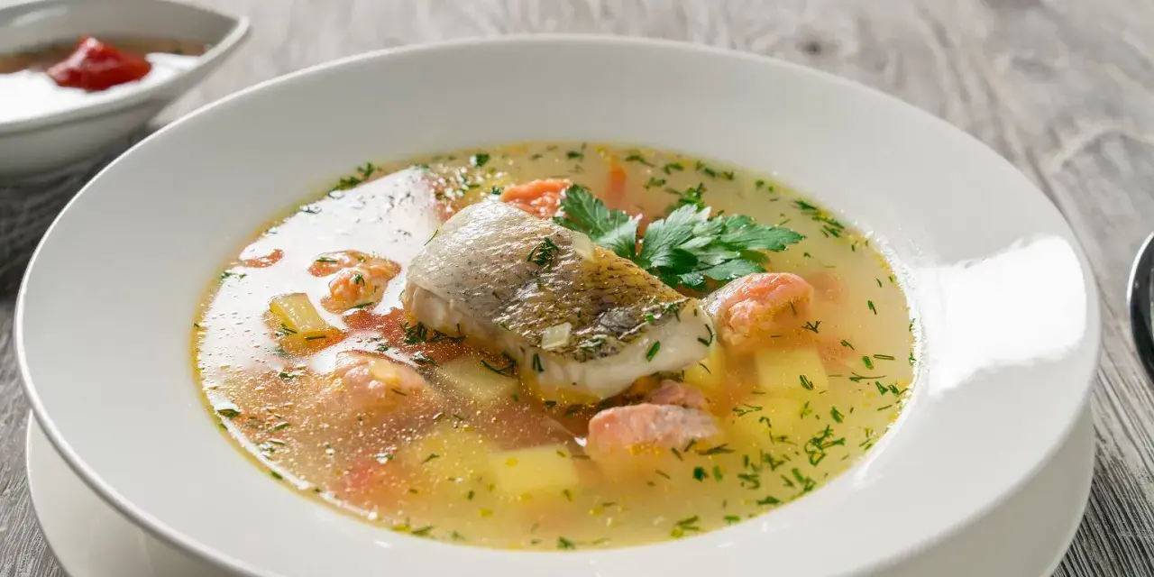 Aromatyczna zupa rybna, przepis babci, z kawałkami ryby, ziemniakami i marchewką, ozdobiona natką pietruszki.