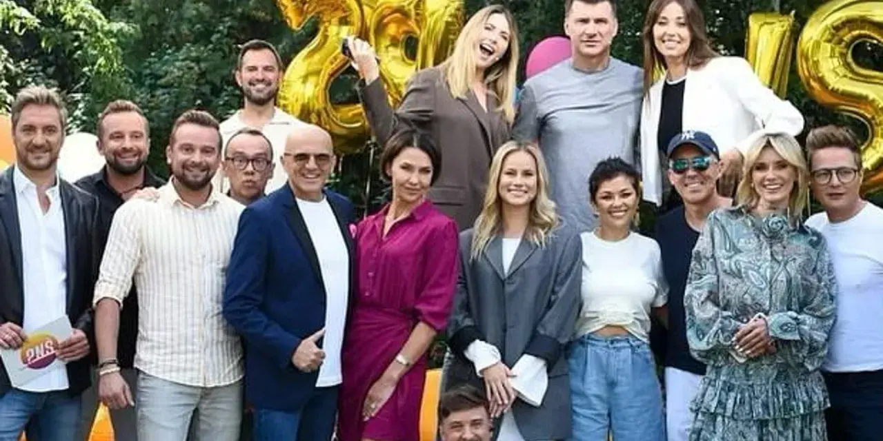 Ekipa TVP2 Pytanie na śniadanie dzisiejszy odcinek świętuje 28 lat! Radosna grupa prezenterów i gości pozuje do wspólnego zdjęcia na tle złotych balonów.