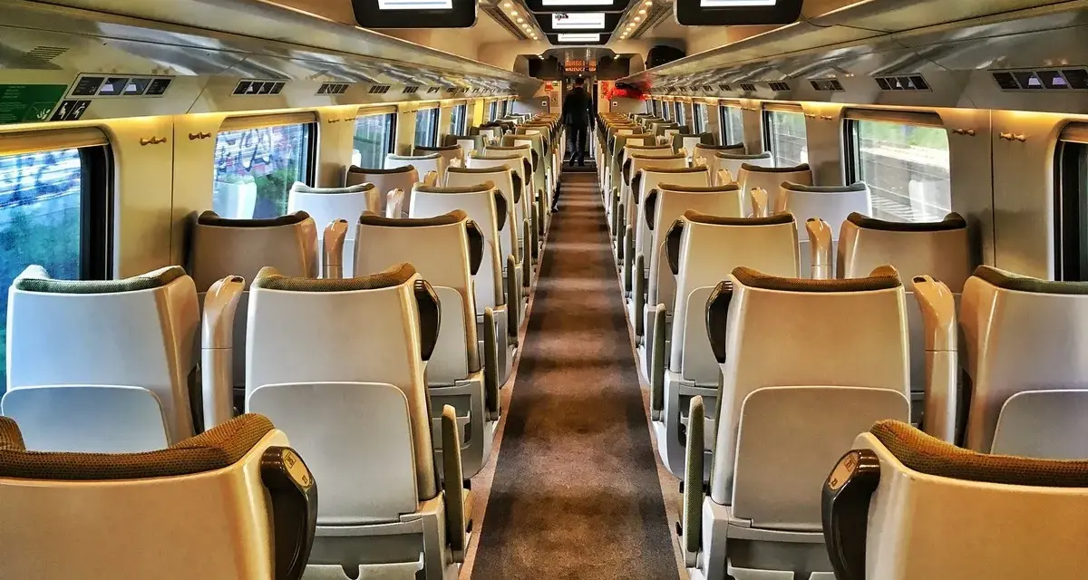 Wnętrze pustego wagonu. Widok na rzędy siedzeń, idealne na podróż pociągiem Kraków - Zakopane.