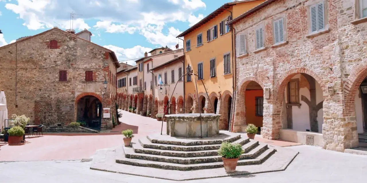 Piazza con pozzo antico e case in pietra e intonaco colorato, un assaggio di cosa vedere a Civitella in Val di Chiana.