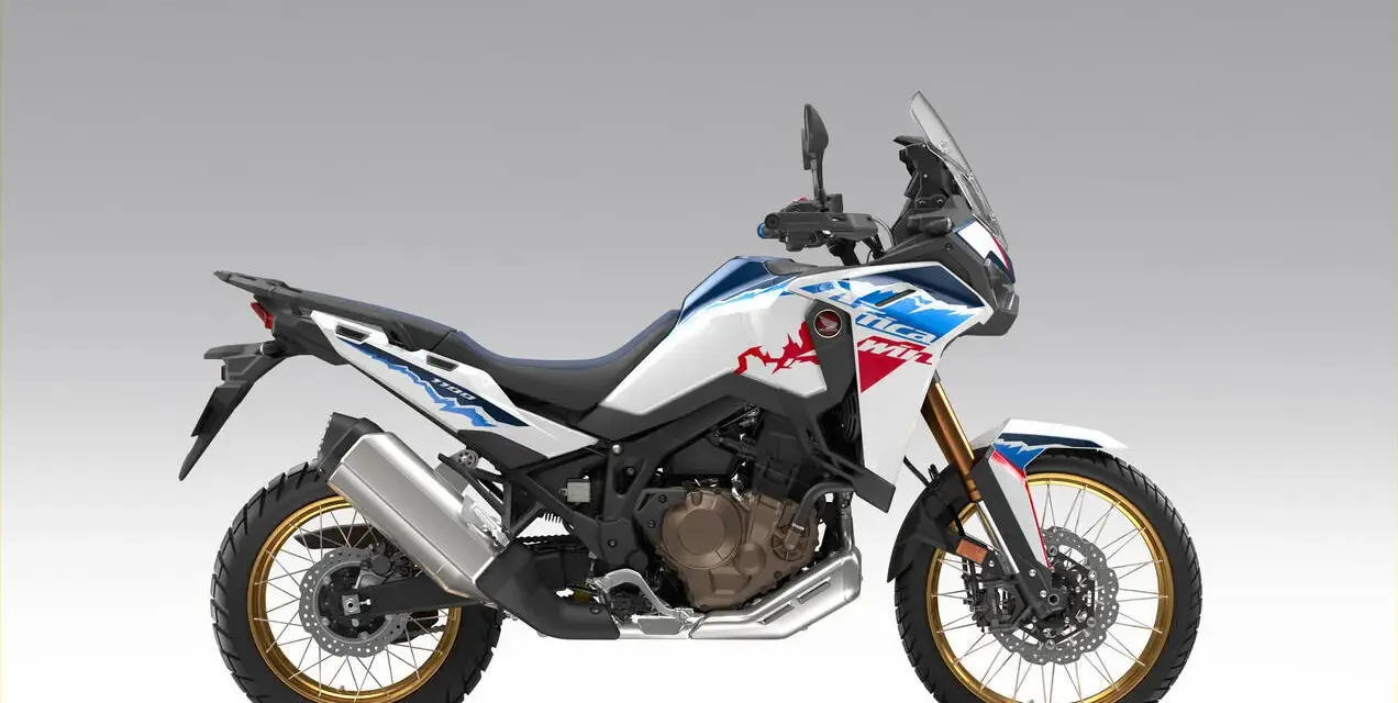 Nowy motocykl Honda Africa Twin 1100 w białym malowaniu z niebieskimi i czerwonymi akcentami, gotowy na przygodę.
