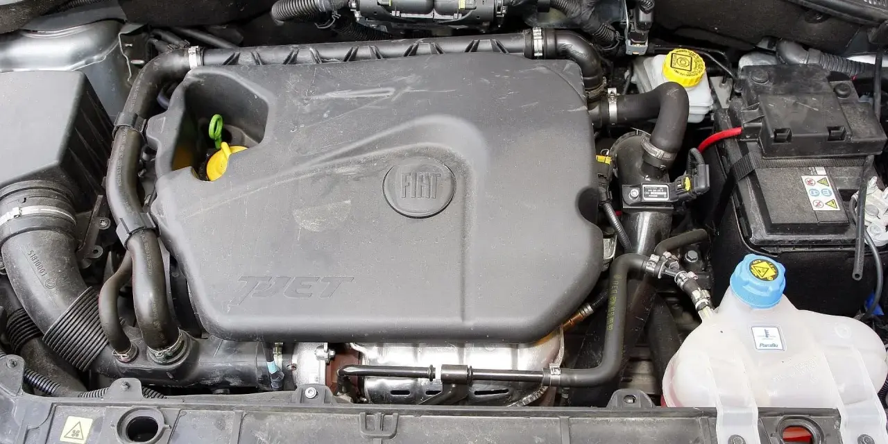 Silnik 1.4 z Fiata Grande Punto. Widoczny plastikowy kolektor, akumulator i zbiornik płynu chłodniczego.