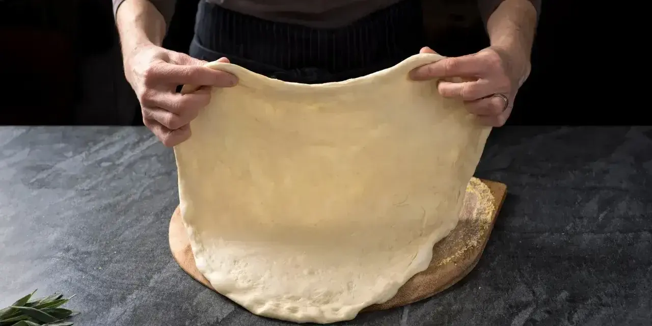Rozciąganie elastycznego ciasta na pizzę, idealnego do szybkiego przepisu na ciasto do pizzy.
