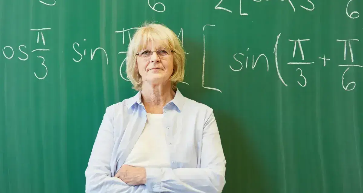 Nauczycielka matematyki przed tablicą z równaniami. Zatrudnienie nauczyciela po 1 września do kiedy umowa?