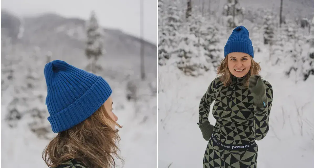 Uśmiechnięta kobieta w zimowym krajobrazie, ubrana w komplet z wełny merino. Jej strój podkreśla właściwości tej naturalnej tkaniny: ciepło i komfort.