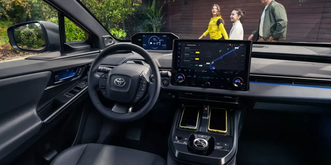 Wnętrze Toyoty bZ4X z ekranem nawigacji. Rodzina na zewnątrz, zastanawia się nad ceną i możliwościami tego elektrycznego SUV-a.