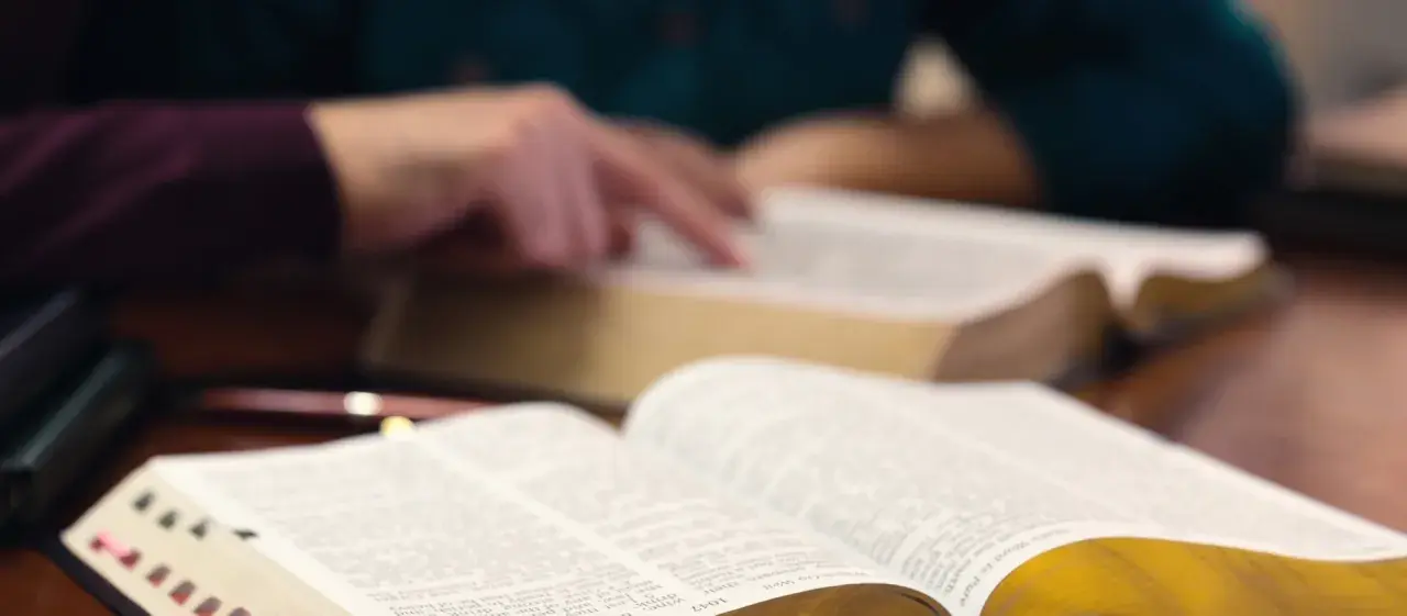 Hände studieren die Bibel, ein Symbol für tiefen Glauben und spirituelle Suche.