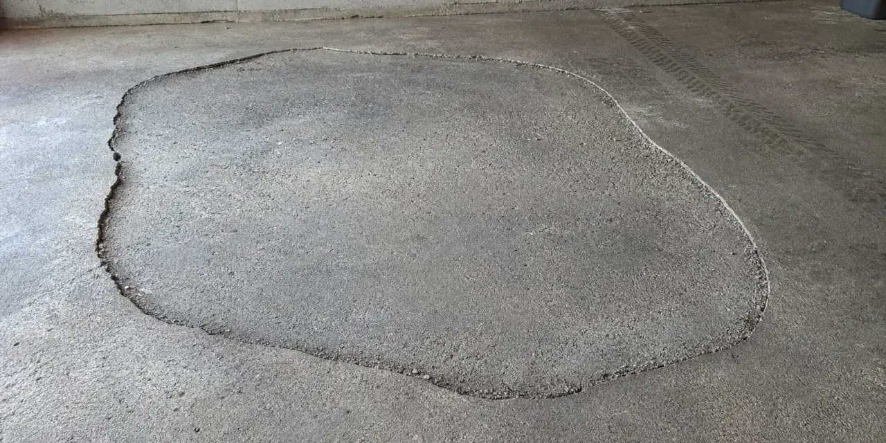 Une large fissure délimite une zone de la terrasse qui s'affaisse, révélant le gravier en dessous.