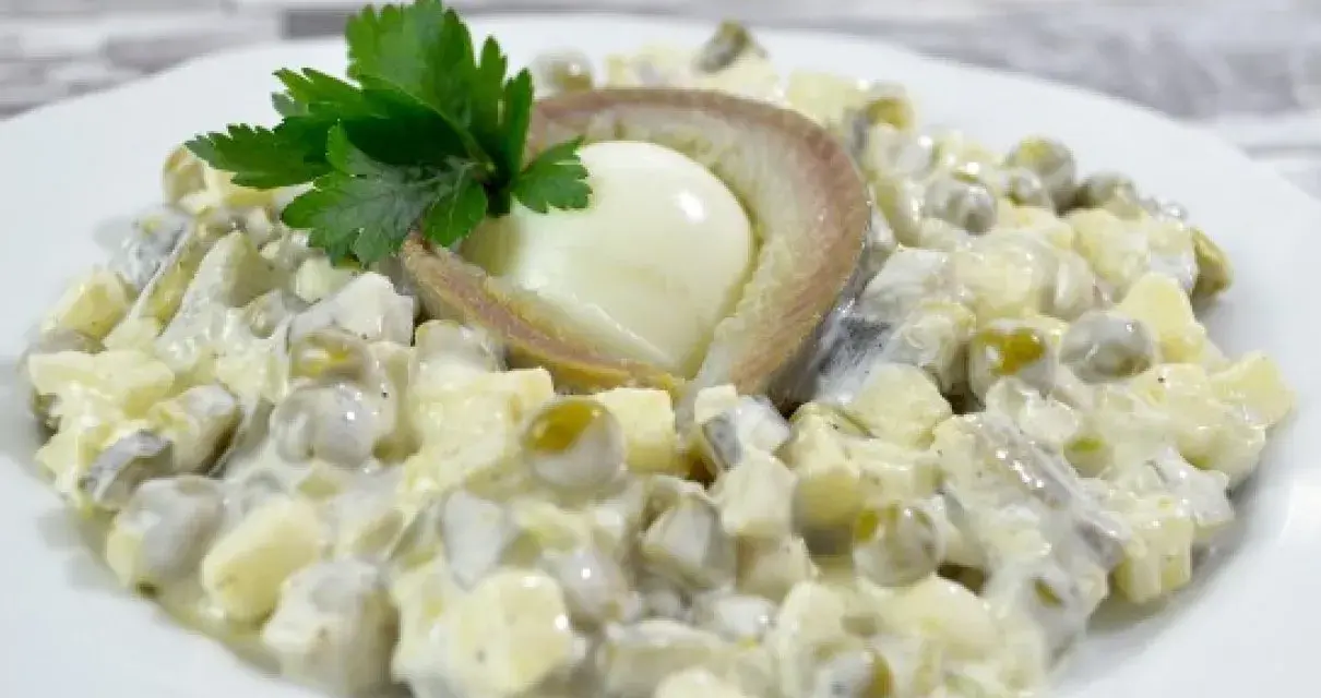 Sałatka z jajkiem, groszkiem i śledziem po japońsku, udekorowana natką pietruszki.