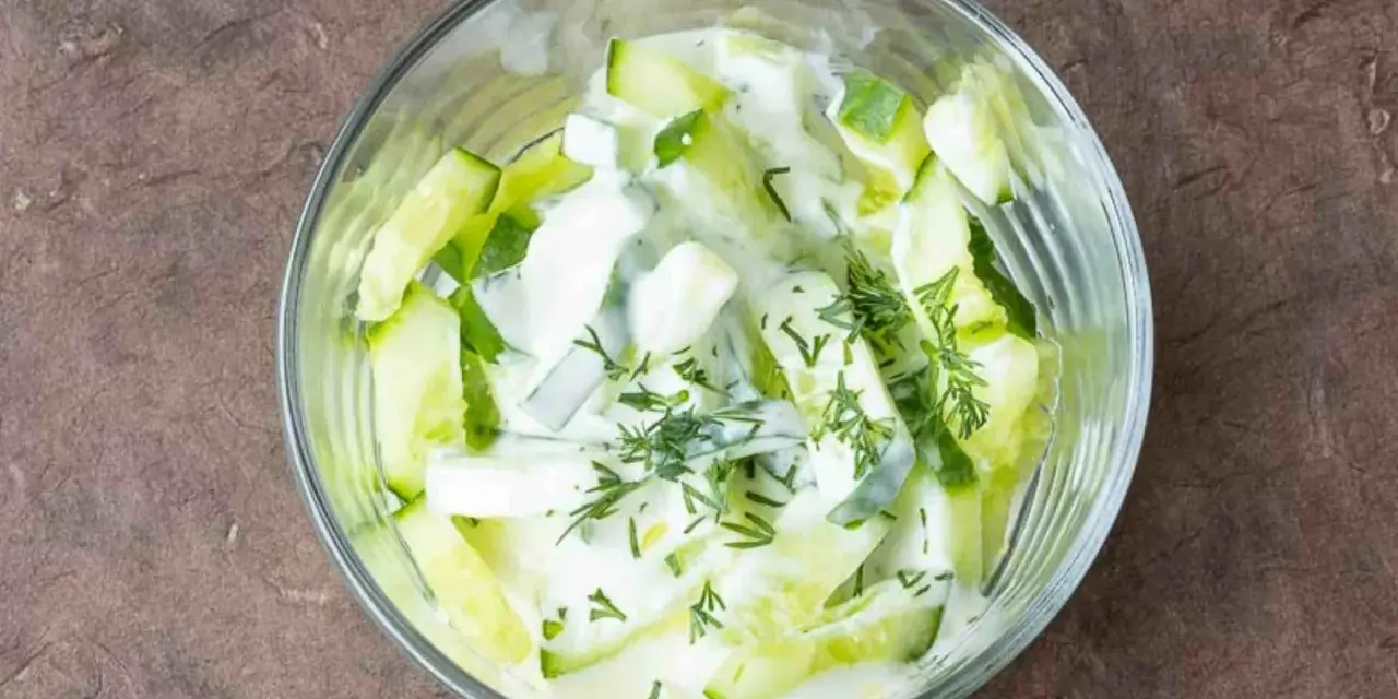 Erfrischender Gurken Dill Salat in einer Glasschüssel, cremiges Dressing mit frischen Kräutern.