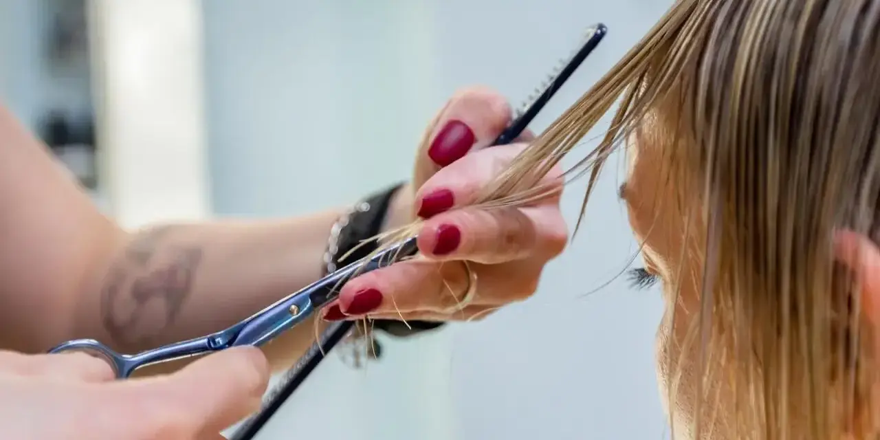 Fryzjerka precyzyjnie modeluje włosy, tworząc delikatne, **wispy bangs**.