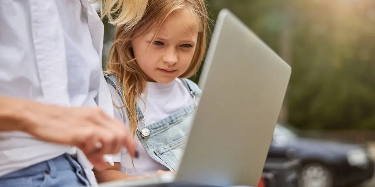 Mama z córką przeglądają internet, szukając informacji, kiedy jest rekrutacja do żłobka.