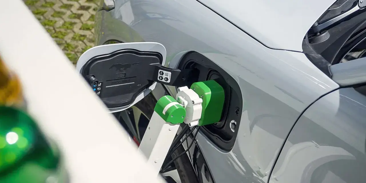 Zielony kabel ładowarki podłączony do portu ładowania samochodu elektrycznego.