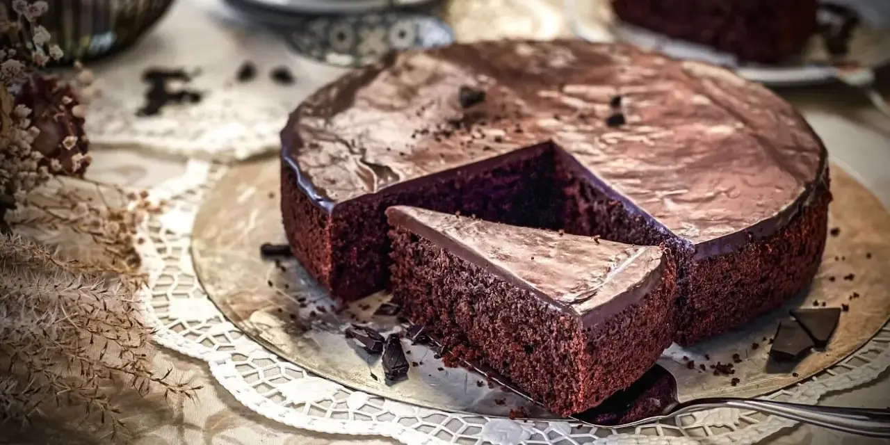Ein saftiger Schokokuchen mit glänzender Glasur, ein Stück herausgeschnitten. Perfekt für ein Schokokuchen Rezept.