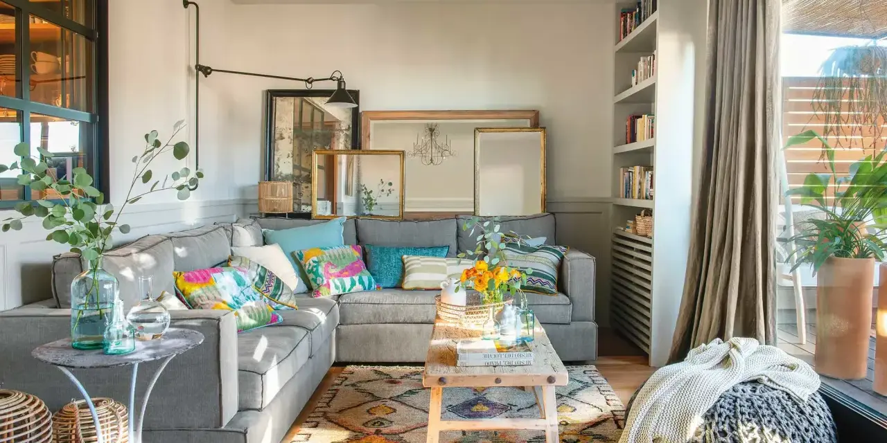 Salones muy pequeños con encanto: sofá gris, cojines coloridos, alfombra étnica, mesa de madera rústica y plantas.