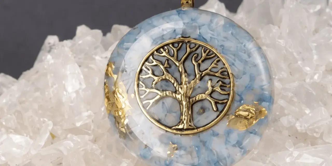 Colgante de orgonita con árbol de la vida dorado sobre fondo de cuarzo. El significado de la orgonita se refleja en su energía protectora.