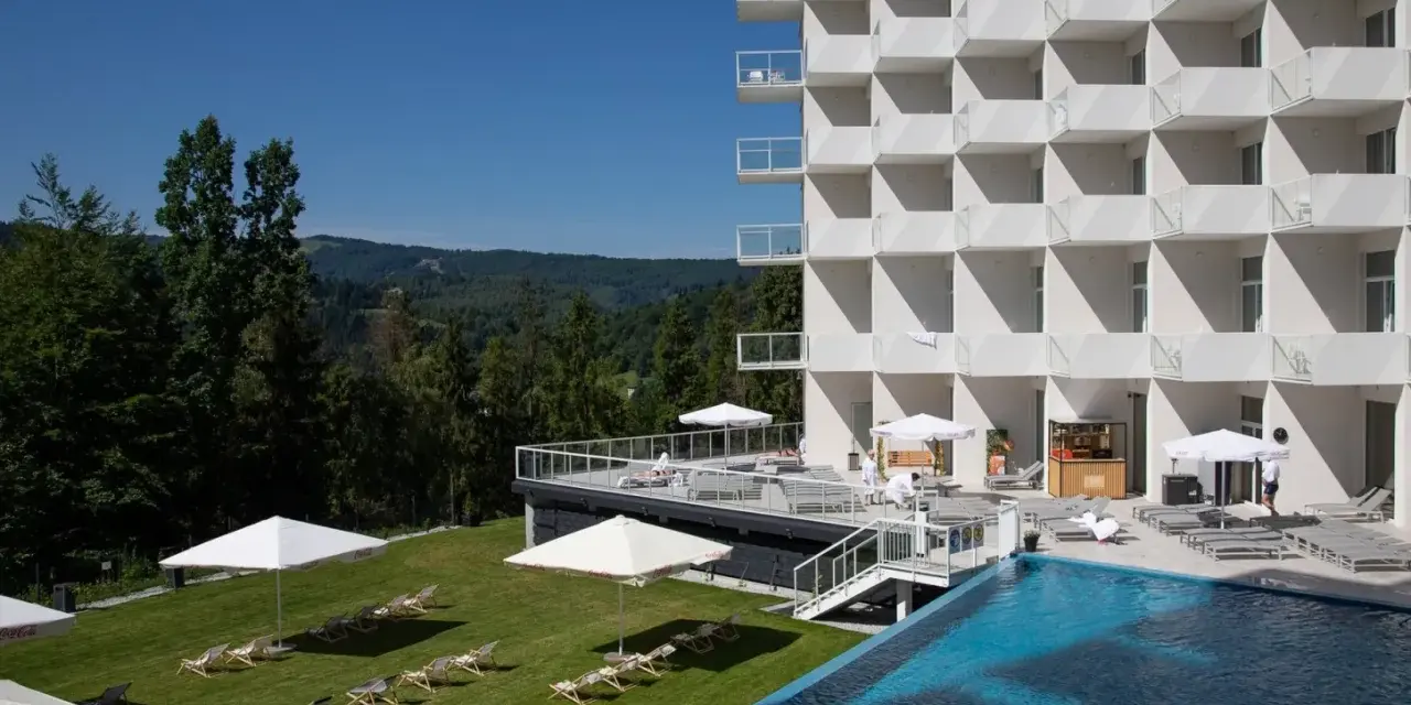 Nowoczesny hotel Crystal Mountain Resort z basenem i leżakami na trawie, otoczony zielonymi wzgórzami.
