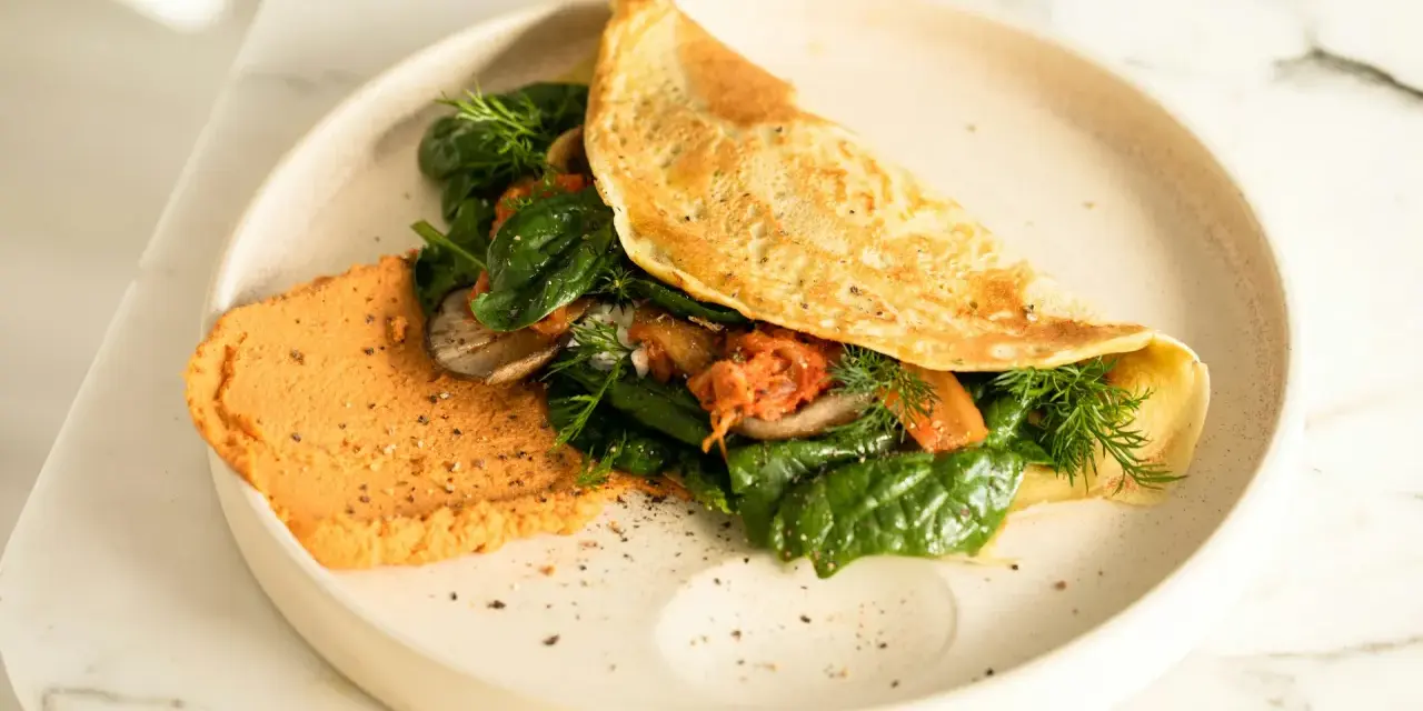 Omlet z air fryera z farszem ze szpinaku, pieczarek i kimchi. Obok porcja pomarańczowego hummusu.
