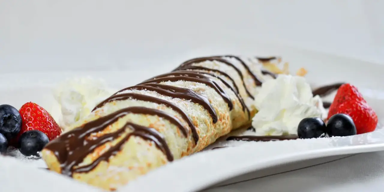 Palatschinken mit Eis, Schokosauce und frischen Beeren. Ein süßer Genuss, der auf der Zunge zergeht.