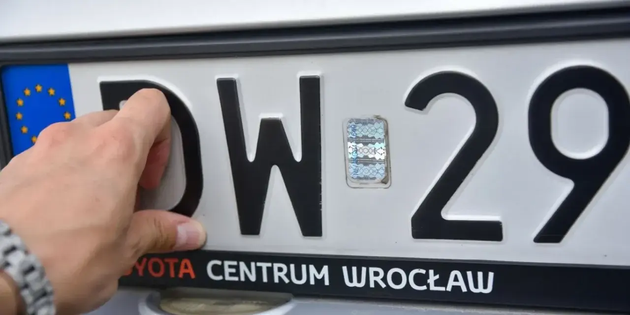 Dłoń zasłania literę "D" na tablicy rejestracyjnej DW 29. Widoczny hologram i napis "TOYOTA CENTRUM WROCŁAW".